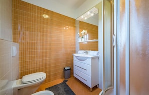 A bathroom with a toilet, sink, and mirror.