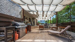 An outdoor patio with a grill, seating, and a covered area with hanging lights. - Beach front apartment in Peroj with WiFi (Peroj)