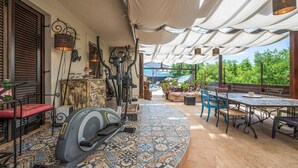 An outdoor patio with exercise equipment, a dining area with chairs and a table, and a patterned tile floor. - Beach front apartment in Peroj with WiFi (Peroj)