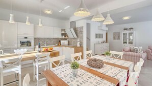 A modern kitchen with white cabinets, a dining area with a wooden table, and pendant lights. - Amazing home in Labin - Rabac (Labin - Rabac)