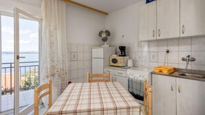 A kitchen with a dining table, chairs, a refrigerator, a microwave, a stove, and a sink. - Beach front apartment in Crikvenica (Crikvenica)