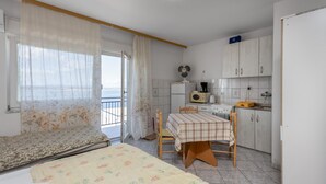 A small, compact room with a bed, a table, and a kitchenette. There is a view through the window to the outside. - Beach front apartment in Crikvenica (Crikvenica)