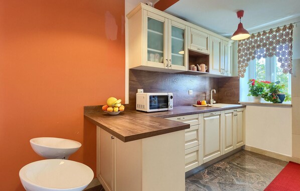 A kitchen with a microwave, sink, and two white stools. - Cozy home in Pazin with WiFi (Pazin)