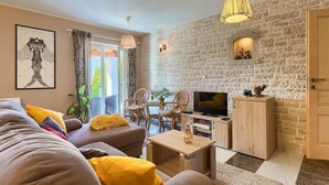 A modern living room with a stone wall, a sofa with yellow cushions, a TV, and a wooden cabinet. - Cozy home in Pazin with WiFi (Pazin)