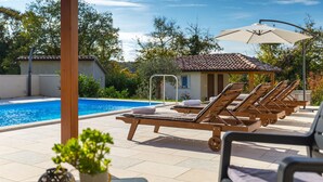A poolside area with lounge chairs and a small building, likely a pool house or changing room, in the background. - Cozy home in Pazin with WiFi (Pazin)