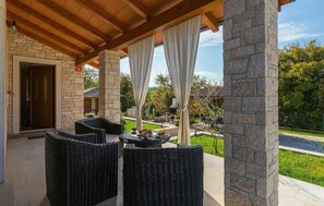 A covered patio area with wicker furniture, stone pillars, and a view of a landscaped garden. - Cozy home in Pazin with WiFi (Pazin)