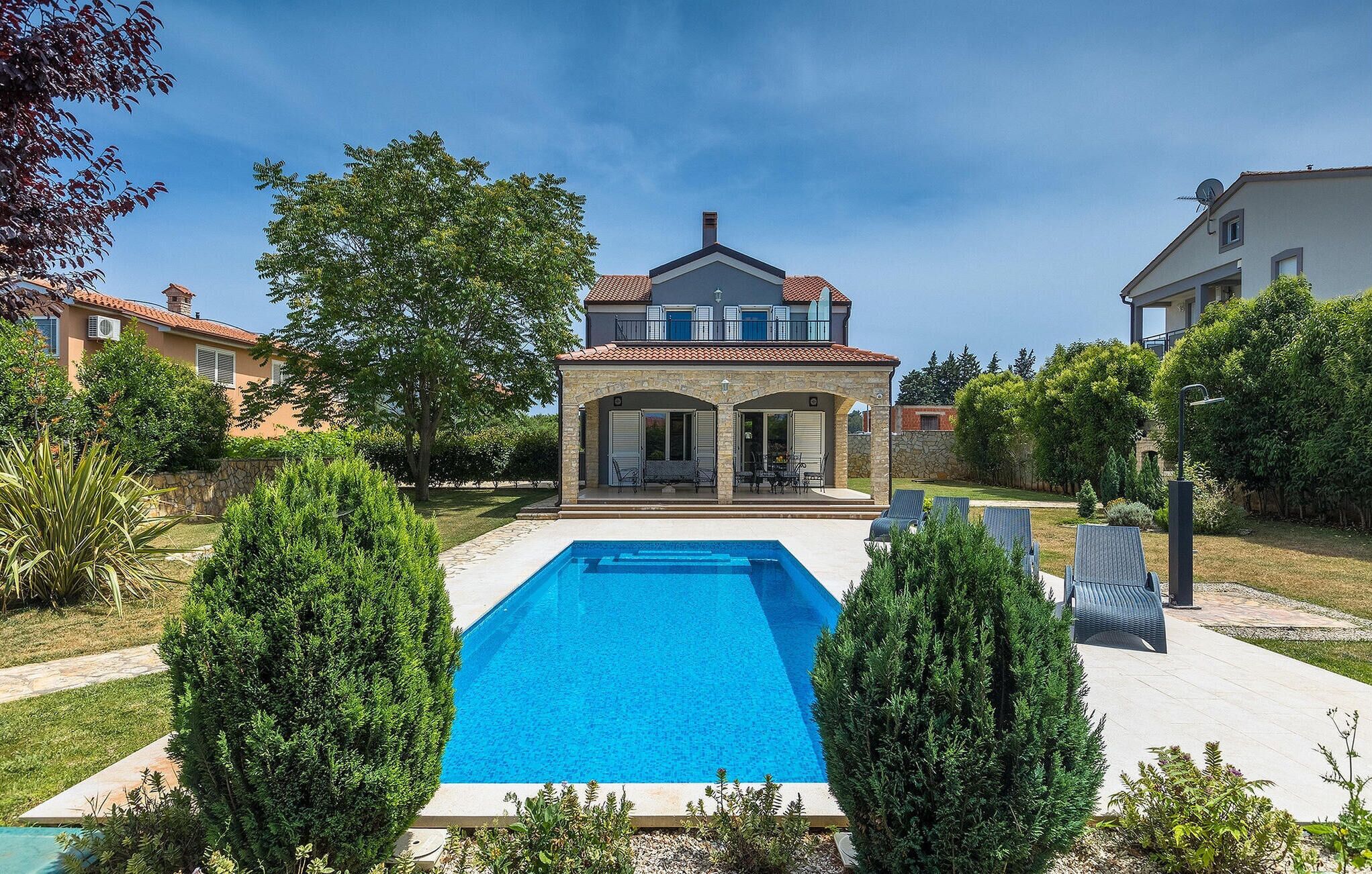 A two-story house with a swimming pool in the front yard.