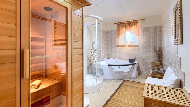 A modern bathroom with a glass-enclosed sauna, a bathtub, and a wooden bench. - Stunning home in Liznjan with sauna (Liznjan)