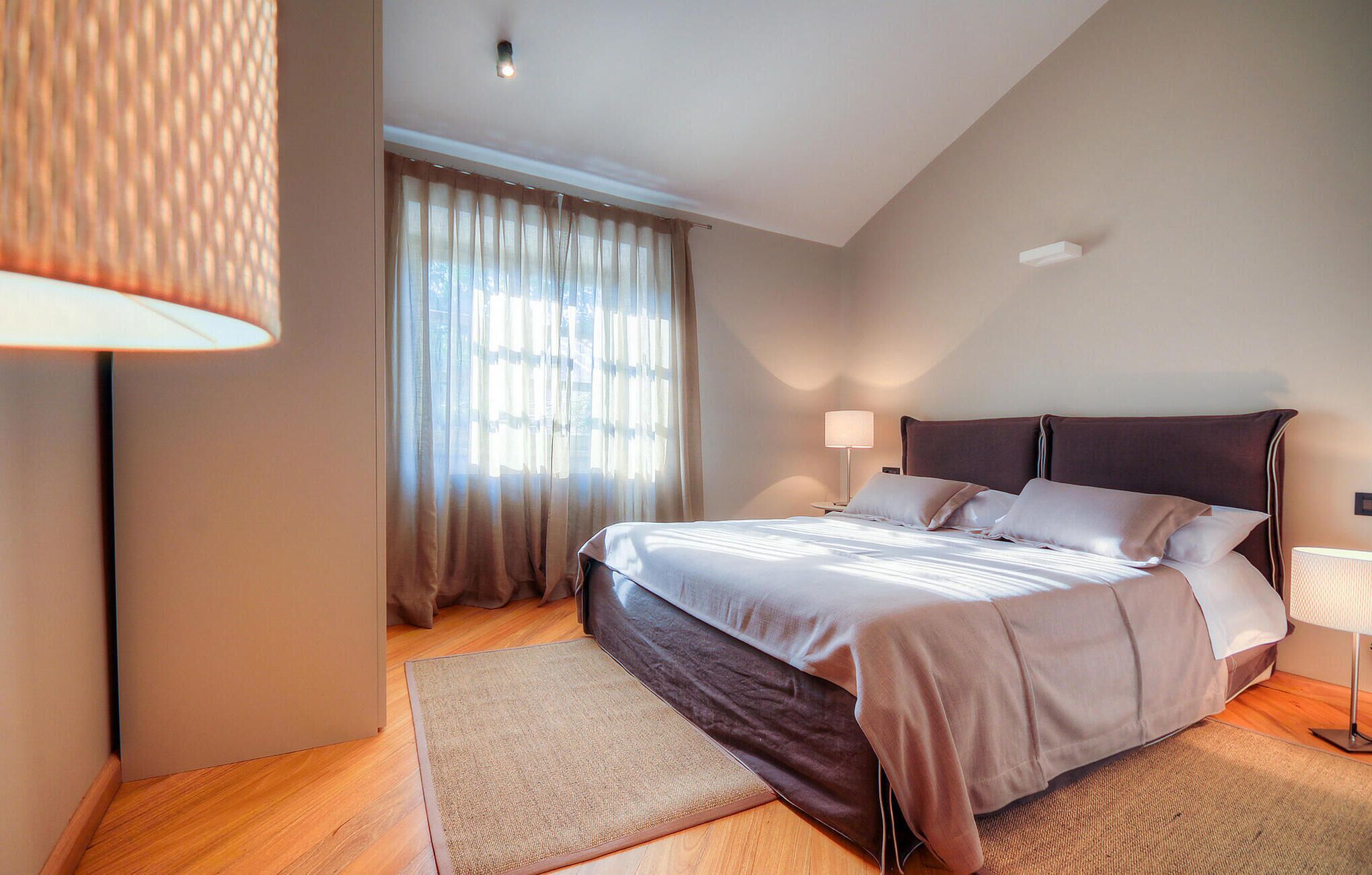 Une chambre à coucher avec un lit, une lampe de chevet, une fenêtre avec des rideaux et une lampe sur pied.