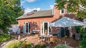 A patio with a table and chairs, a covered seating area, and a brick building with a window and door. - Awesome home in Ausacker with WiFi (Ausacker)