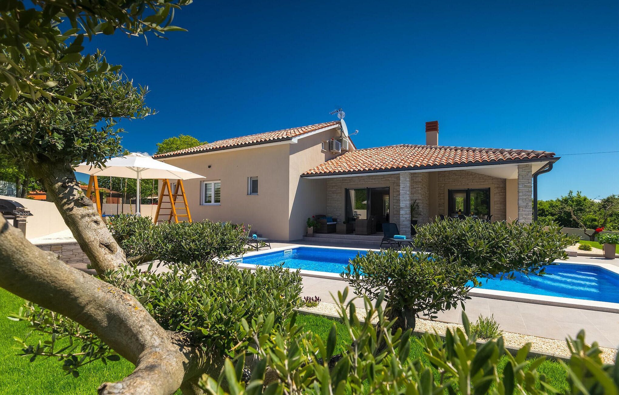A two-story house with a swimming pool, a covered patio, and a garden.