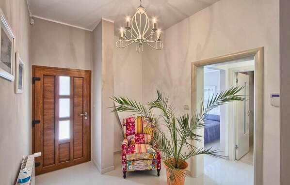 A hallway with a wooden door, a colorful armchair, a potted plant, and a chandelier. - Gorgeous home in Pula (Pula)