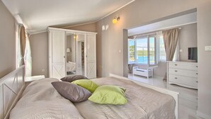 A bedroom with a large bed, a wardrobe, a dresser, and a view of the outdoors. - Gorgeous home in Pula (Pula)