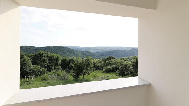 Ein Zimmer mit großem Fenster und Blick auf eine grüne Landschaft mit Hügeln.