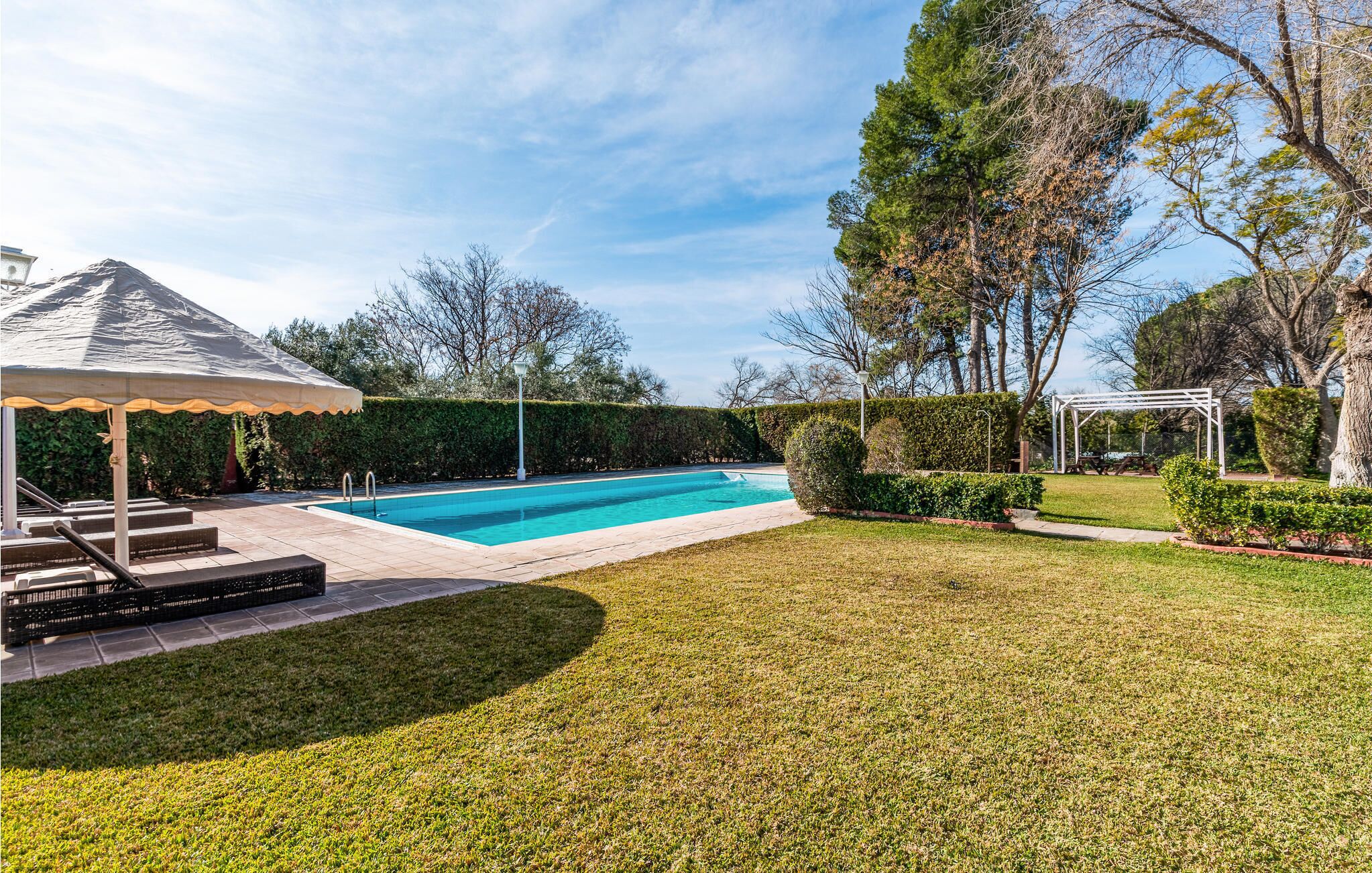 Une piscine agrémentée d’une pergola et d’un kiosque, le tout situé dans un jardin aménagé.