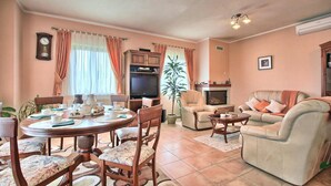A living room with a round dining table, chairs, a sofa, a television, and a fireplace. - Awesome home in Pican (Pican)