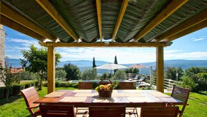A wooden pergola with a table and chairs, overlooking a scenic landscape with mountains and trees. - Awesome home in Pican (Pican)