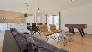 Una sala moderna con sofá, sillones y una mesa de fútbol.