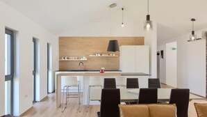 Una cocina moderna con una isla central, armarios blancos e iluminación colgante.