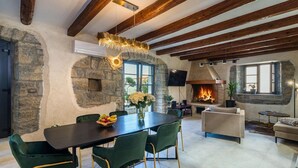 A spacious living area with a stone fireplace, a dining table with chairs, and a cozy seating area with a sofa and armchair. - Amazing home in Pazin (Pazin)