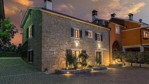 A stone building with a traditional facade, multiple windows with shutters, and a well-lit entrance. - Amazing home in Pazin (Pazin)