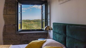 A bedroom with a stone wall, a bed with green headboard, and a window overlooking a green landscape. - Amazing home in Pazin (Pazin)