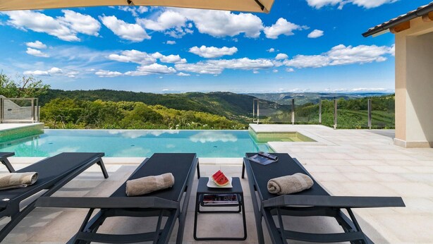 An infinity pool with lounge chairs and a view of a mountainous landscape. - Amazing home in Pazin (Pazin)