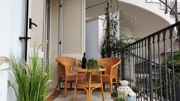 A balcony with wicker furniture, a small table, and a potted plant.