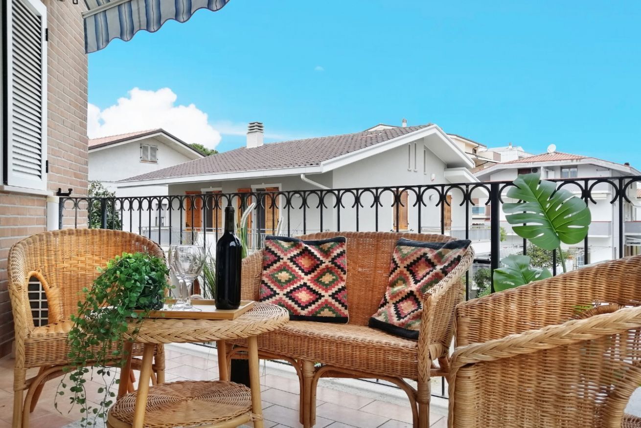 A wicker outdoor seating area with a table, a bottle, and a potted plant.