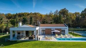 Une maison moderne à deux étages dotée d’une piscine, d’un espace salon extérieur et d’un jardin.