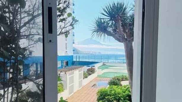 A view from a balcony with a pool, palm trees, and a distant mountain. - NEAR THE SEA IN MESA DEL MAR (Mesa del Mar)