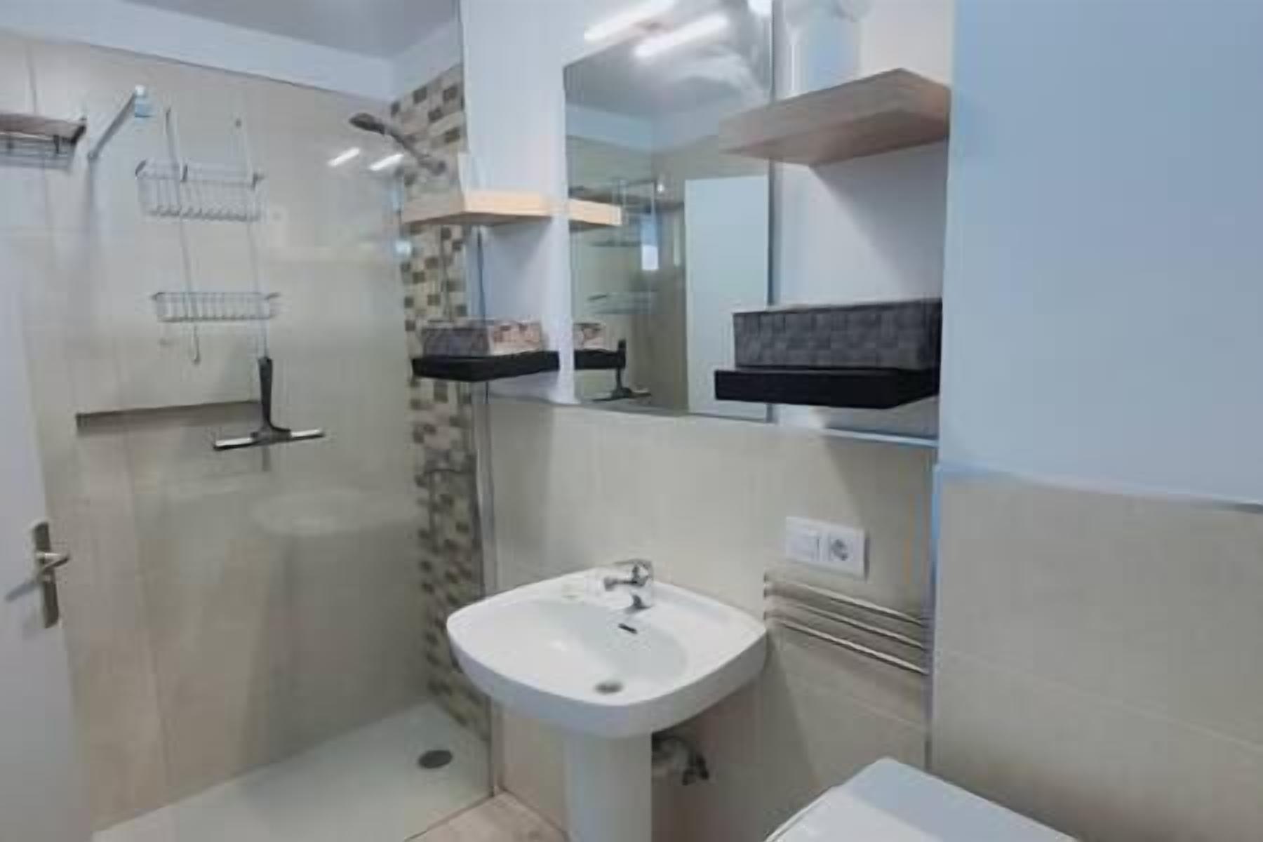 Une salle de bain avec une douche, un lavabo et un miroir.