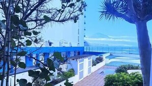 A coastal hotel with a blue and white facade, a paved walkway, and a view of the sea. - NEAR THE SEA IN MESA DEL MAR (Mesa del Mar)