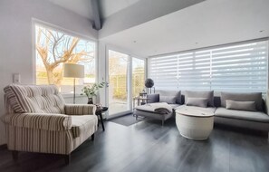 A modern living room with a striped armchair, a grey sofa, and a round coffee table. There are large windows with blinds, a floor lamp, and a decorative globe on a side table. - 3 bedroom awesome home in Stavenisse (Stavenisse)