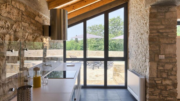 Una cocina moderna con paredes de piedra, ventanas amplias y techo de madera.