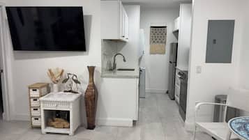A modern kitchen with white cabinetry, a built-in sink, and a stainless steel refrigerator.