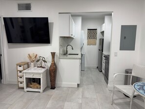 A modern kitchen with white cabinetry, a built-in sink, and a stainless steel refrigerator.