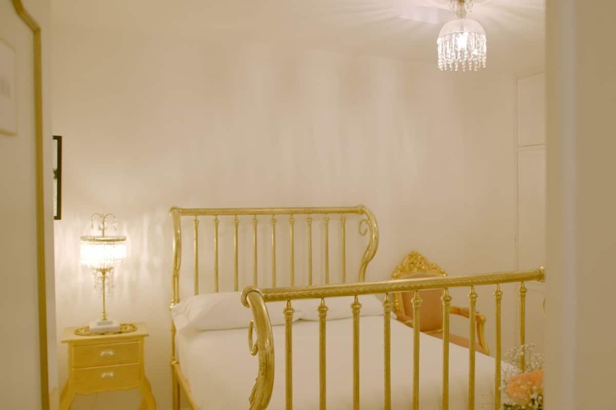 Un dormitorio con cama, mesita de noche, candelabro y puerta.