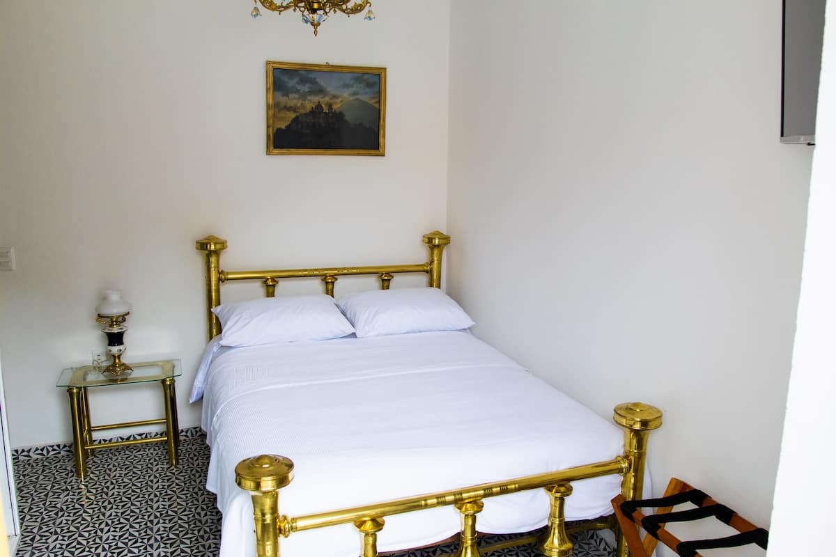 Una habitación con una cama, una mesita de noche, una lámpara y un cuadro en la pared.