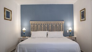 Un dormitorio con una cama, dos mesitas de noche y dos lámparas de pared.
