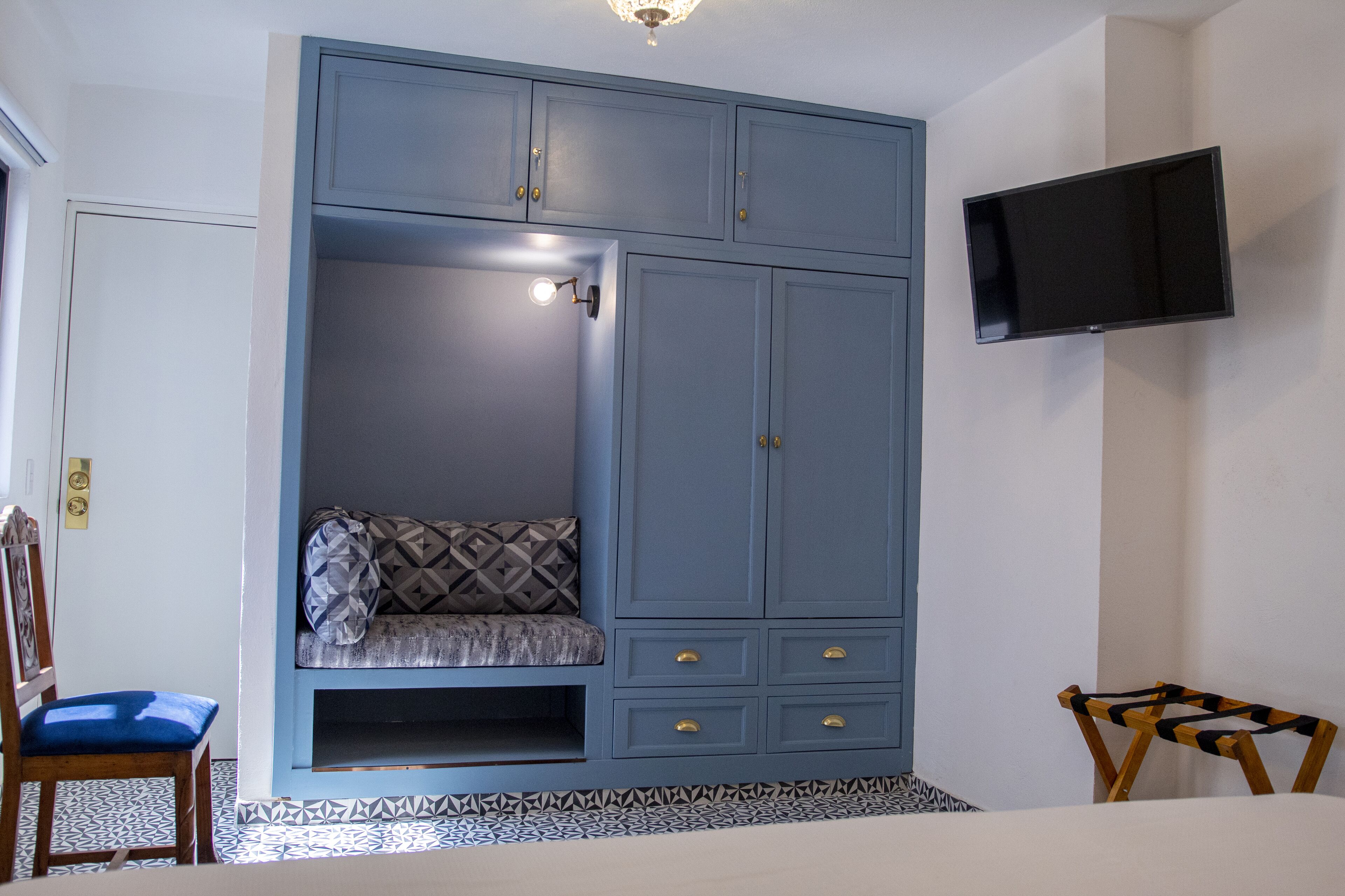 A bedroom with a built-in wardrobe, a television mounted on the wall, and a patterned floor.
