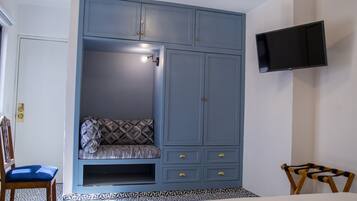 A bedroom with a built-in wardrobe, a television mounted on the wall, and a patterned floor.