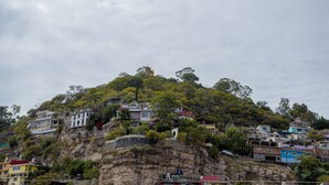 Una ladera con edificios coloridos, algunos con balcones, y un acantilado rocoso.