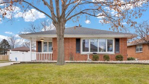 A single-story brick house with a covered porch, a large window, and a tree in the front yard. - 3 Bedroom, cozy house in Milwaukee near airport (Milwaukee)