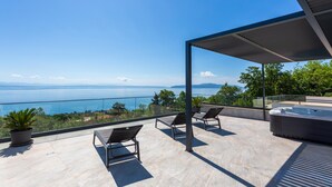 Ein Balkon mit zwei Liegestühlen, einem kleinen Tisch und einem Blumentopf.