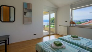 A bedroom with two beds, a large window with a view, a mirror, and a radiator. - Amazing home in Kostrena with sauna (Kostrena)