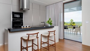 A modern kitchen with a Bosch oven, a stainless steel range hood, and a bar area with two wooden stools. - Lovely home in Labin - Rabac (Labin - Rabac)