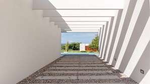 A modern architectural corridor with a geometric design, leading to an outdoor area with greenery and a building in the background. - Lovely home in Labin - Rabac (Labin - Rabac)