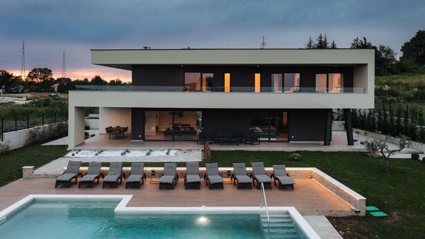 Une maison moderne à deux étages, dotée d’une piscine, d’un espace extérieur aménagé et d’un jardin bien entretenu.
