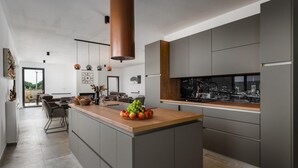 Une cuisine moderne avec des meubles gris, un plan de travail en bois et une vue sur le paysage urbain par la fenêtre.